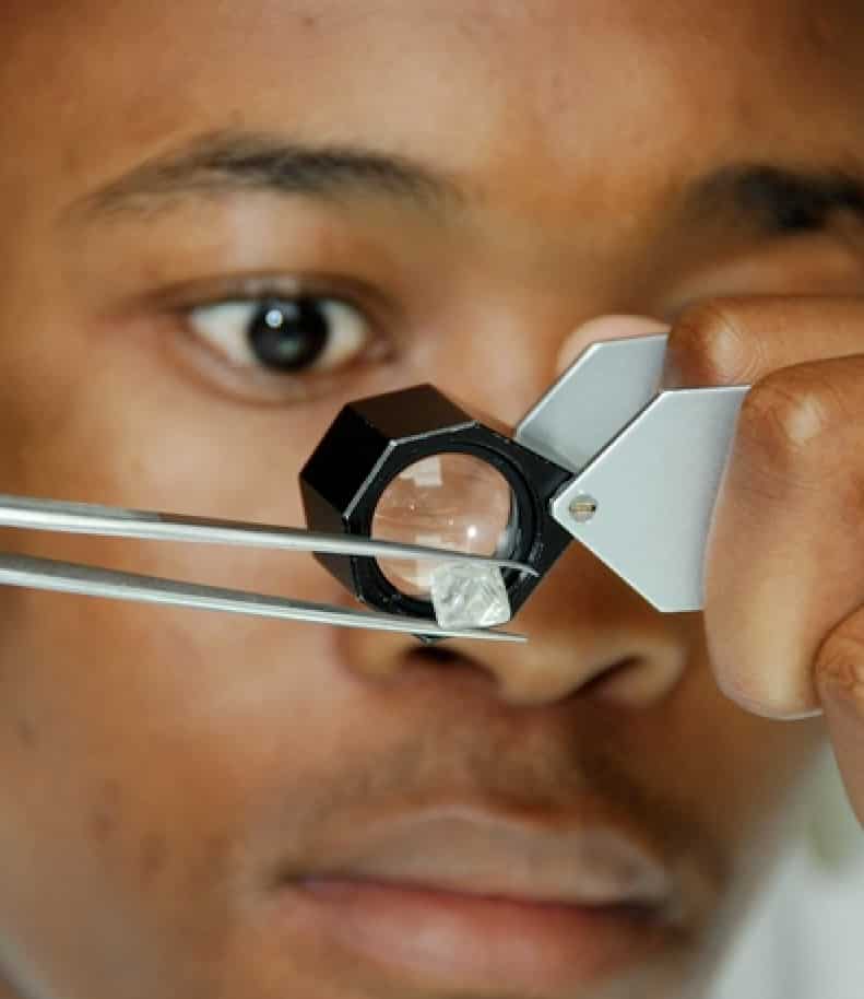 Examining a diamond under a magnifying glass