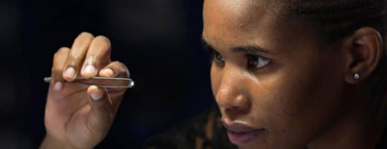 woman with tweezers holding a sparkling diamond